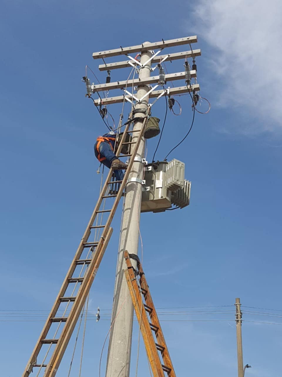 Eletricista da Zentrix com cinto de segurança montando subestação simplificada em poste com transformador